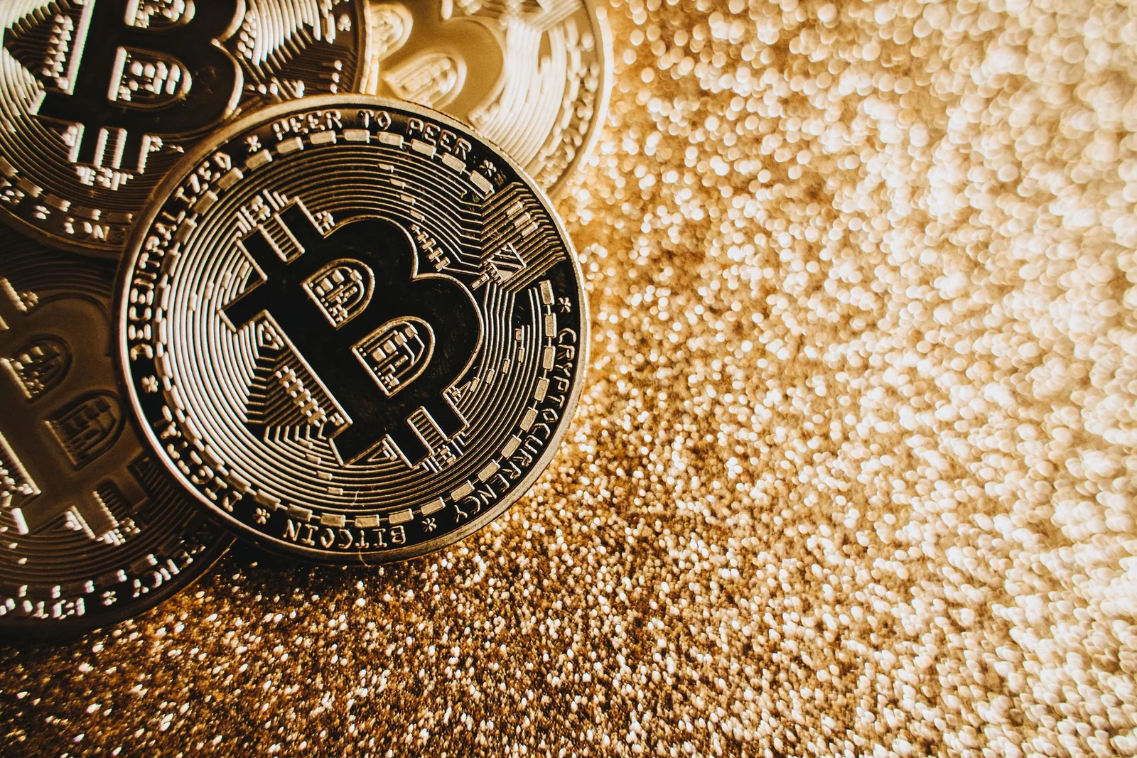 Musta bitcoin-kolikko kultaisten kolikoiden päällä kimaltavalla pinnalla