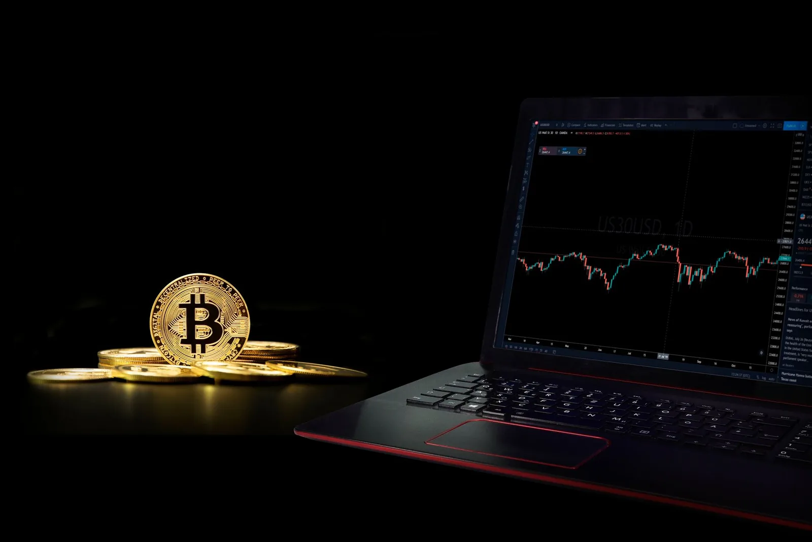 Bitcoin-kolikko pimeässä kannettavan tietokoneen ja kaavion vieressä