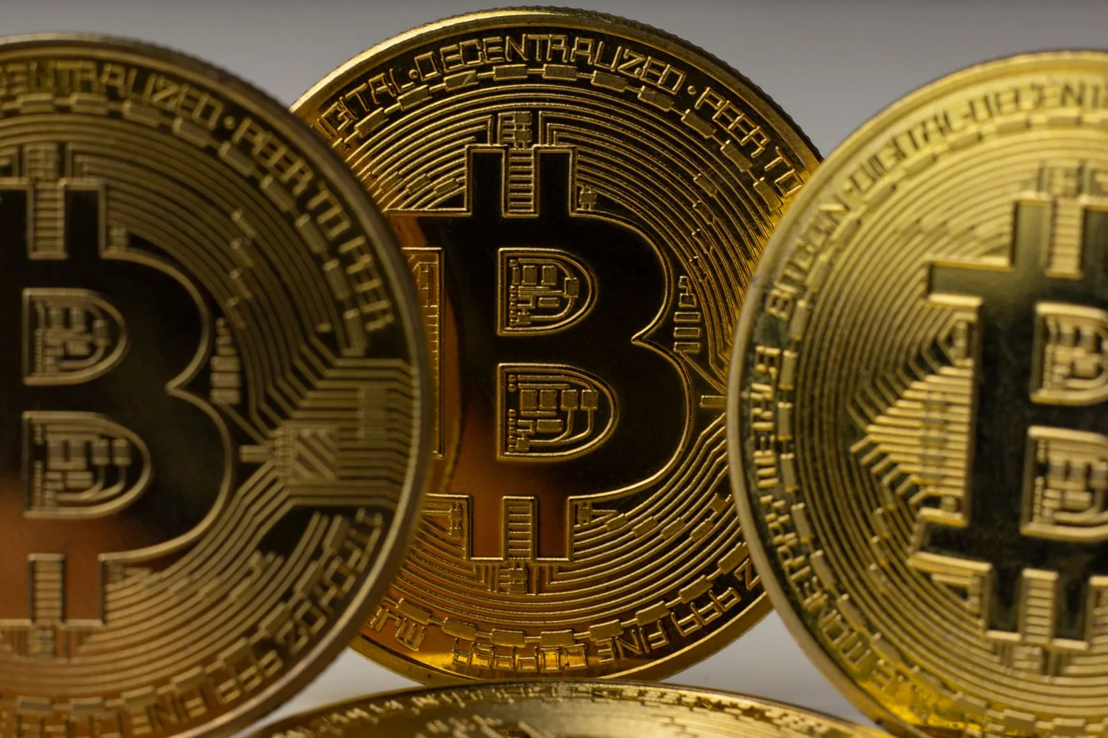 Kolme suurta kultaista bitcoin-kolikkoa lähikuvassa