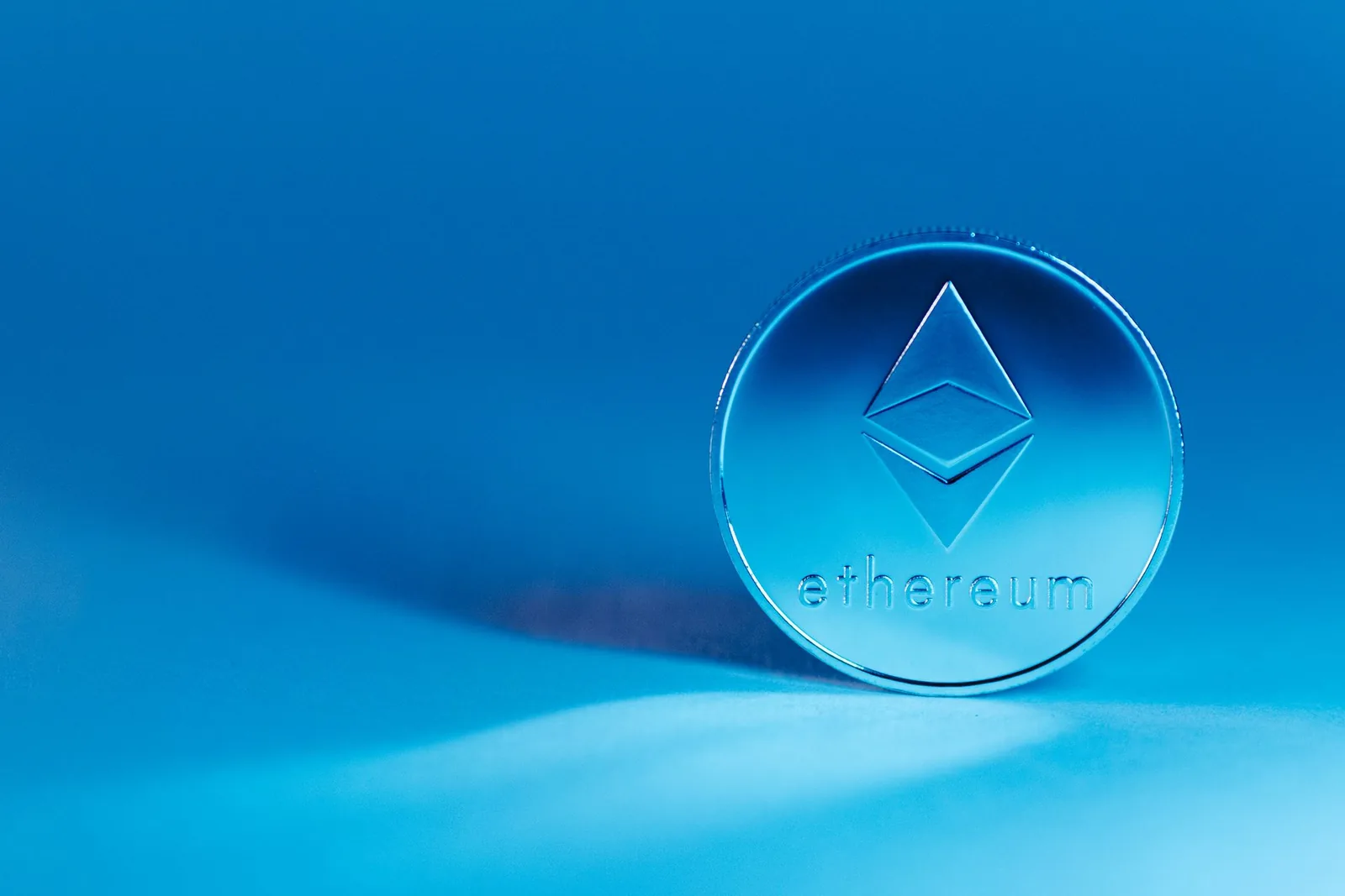 Läpikuultava Ethereum-kolikko sinistä taustaa vasten