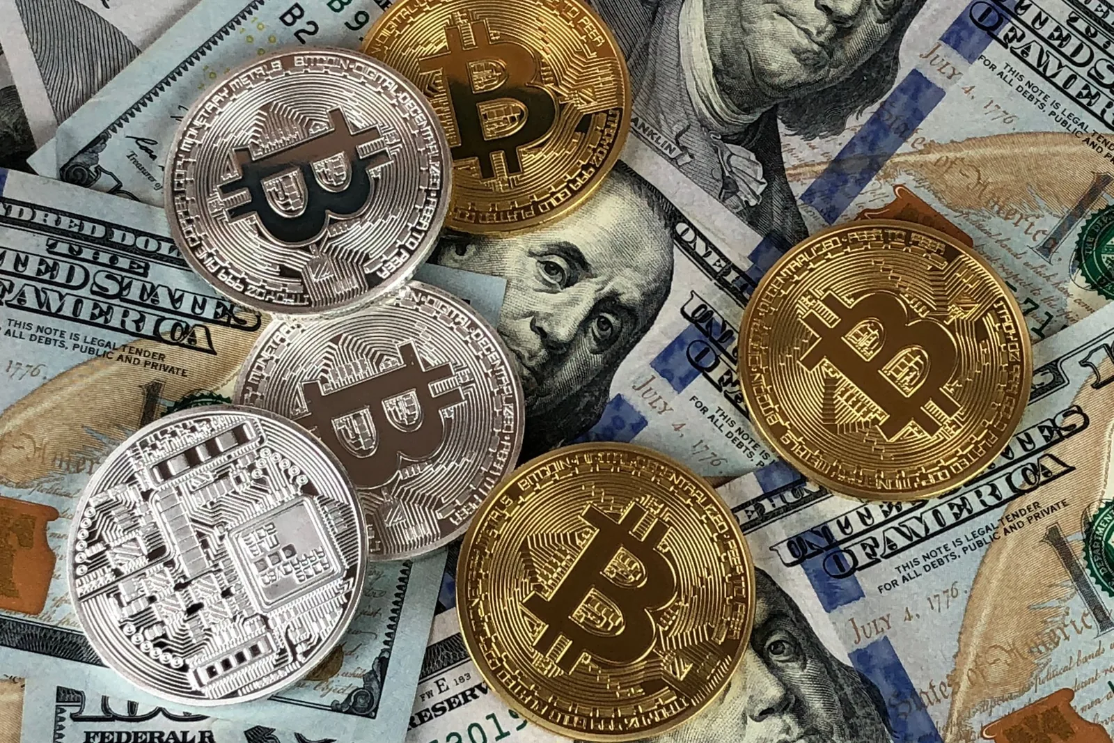 Bitcoin-kolikoita dollarin seteleiden päällä