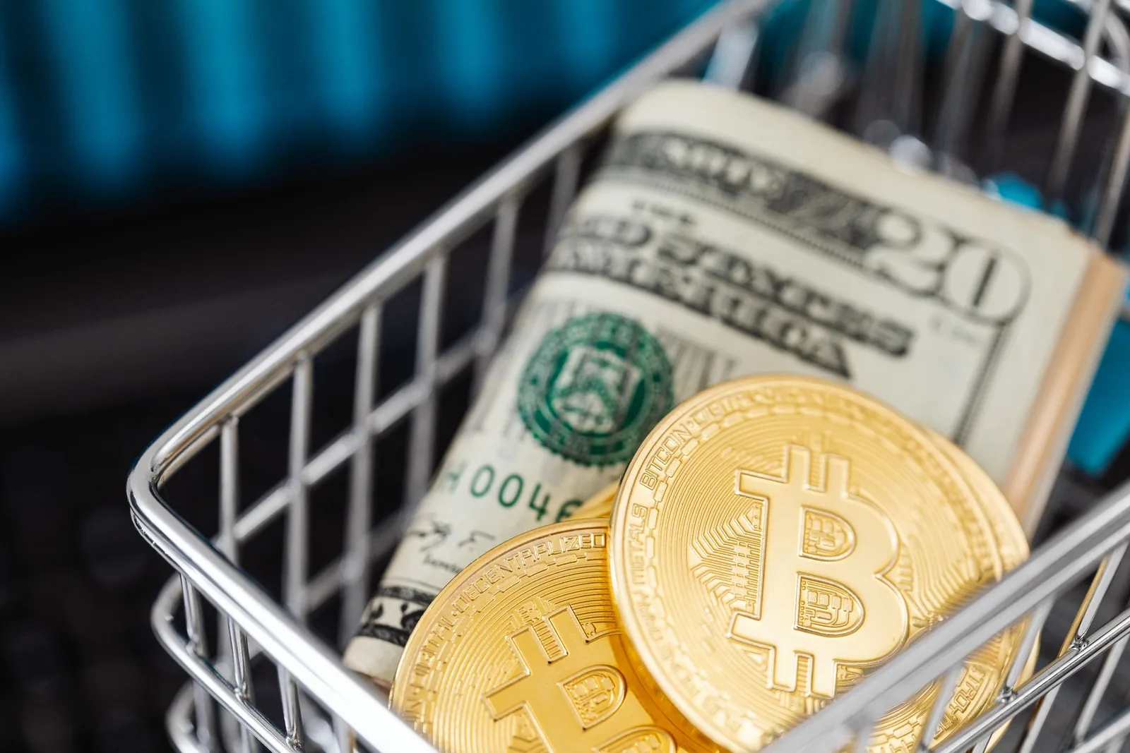 Kauppakori, jossa dollarin seteleitä ja bitcoin-kolikoita