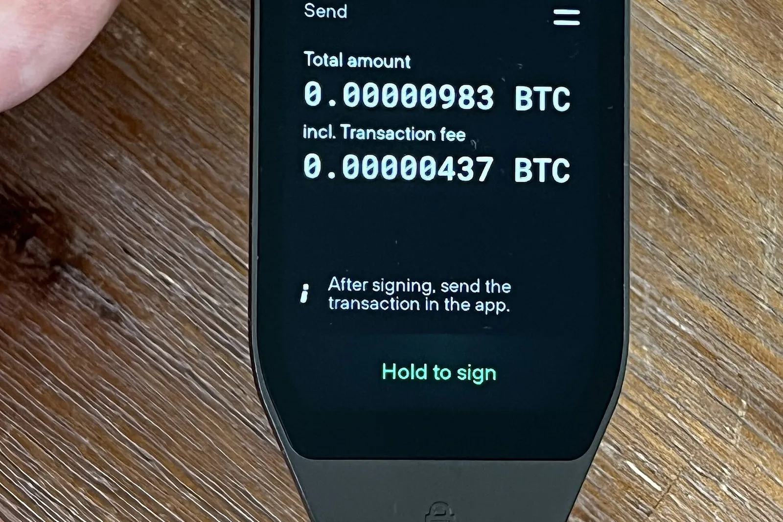 Kädessä pidettävä laitelompakko, jonka näytöllä bitcoin-saldo