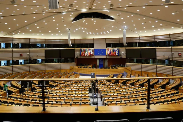 Euroopan parlamentin täysistuntosali tyhjänä, penkkirivit ja sinisiä lippuja