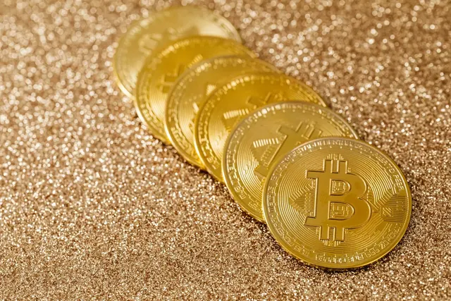 Rivi kultaisia bitcoin-kolikoita kimaltavalla pinnalla