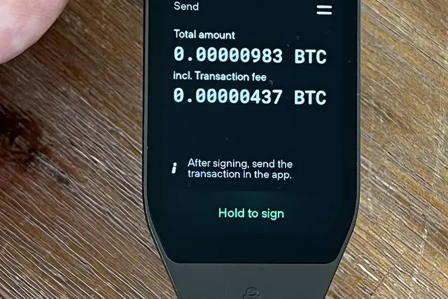 Kädessä pidettävä laitelompakko, jonka näytöllä bitcoin-saldo